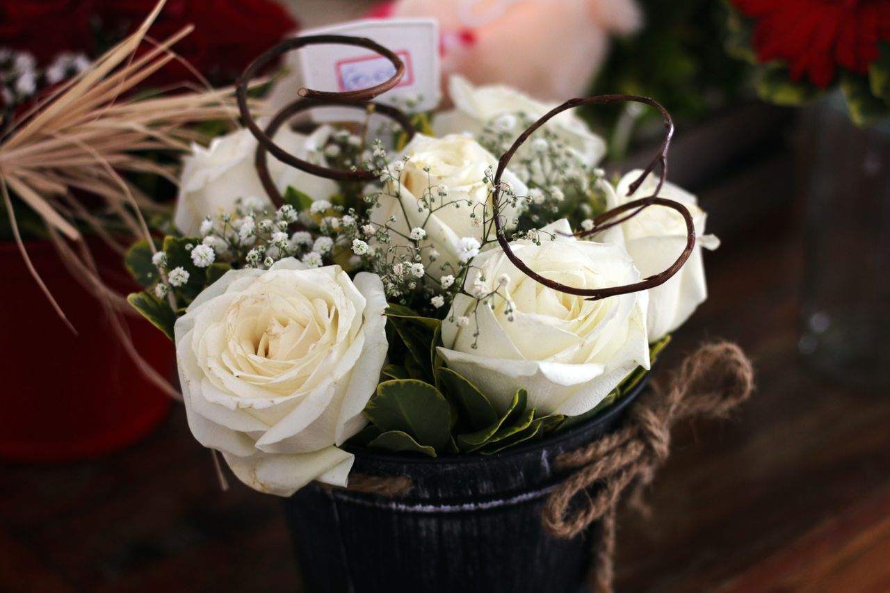 Close-up of elegant white roses in a decorative bucket, ideal for weddings or home decor.